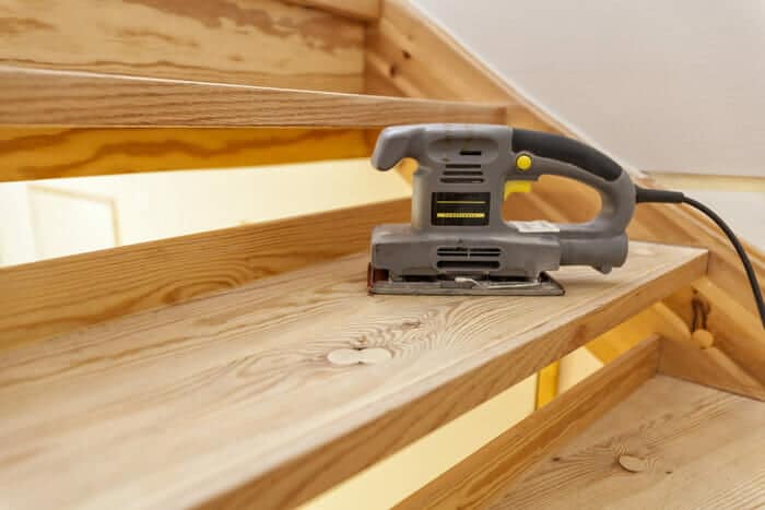 closeup of a sheet sander sitting idle on a wooden staircase