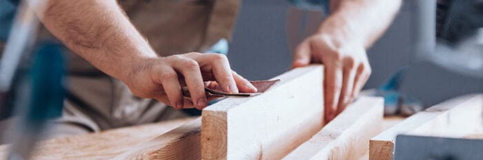 a carpenter sanding a length of wood by hand