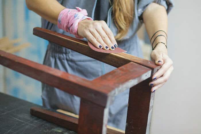 woman sanding a wooden table by hand